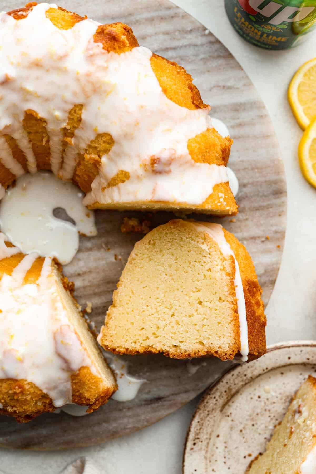 Top down shot of the 7Up bundt cake on a serving platter next to a can of 7Up and lemon slices. 