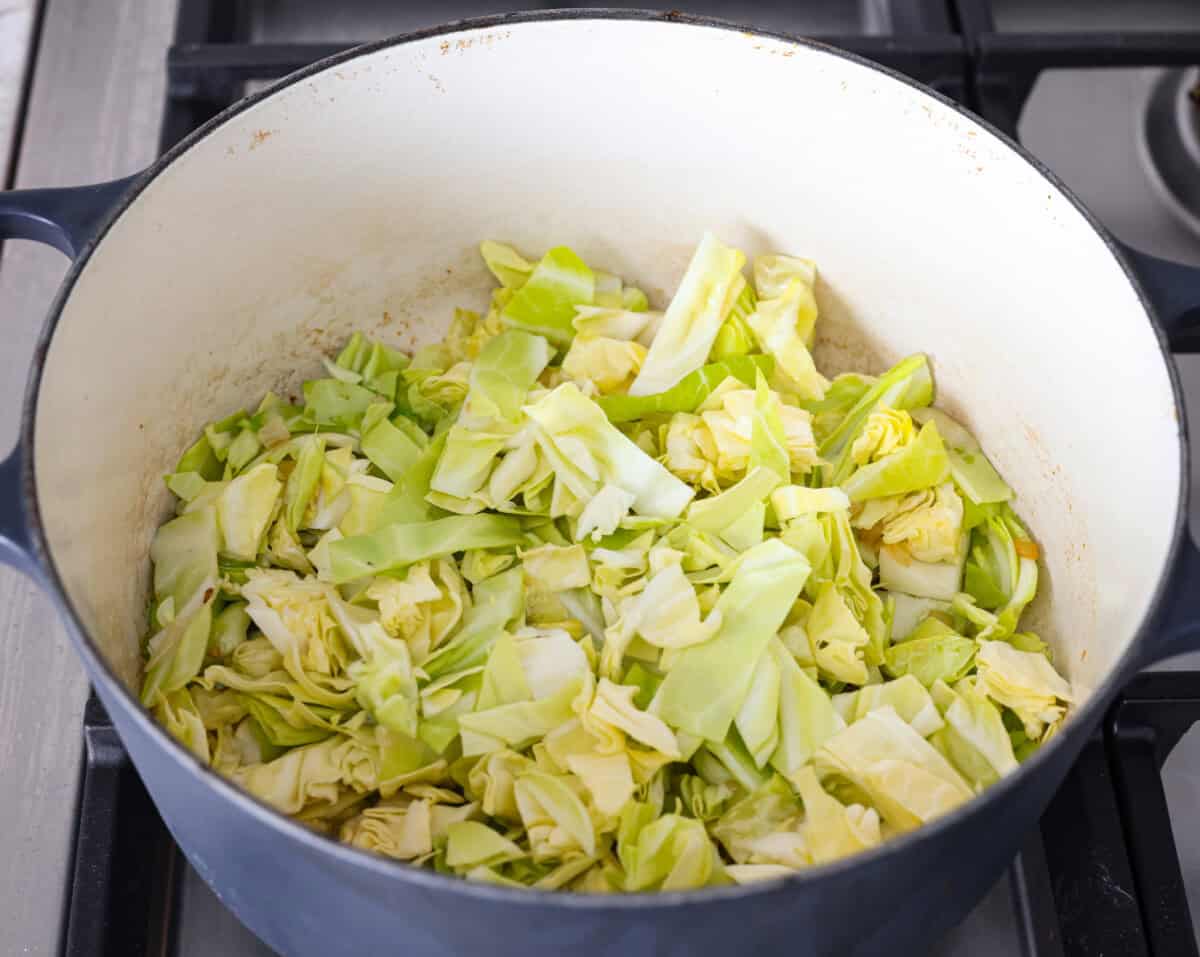 Overhead shot of cabbage added to the butter onions and garlic. 