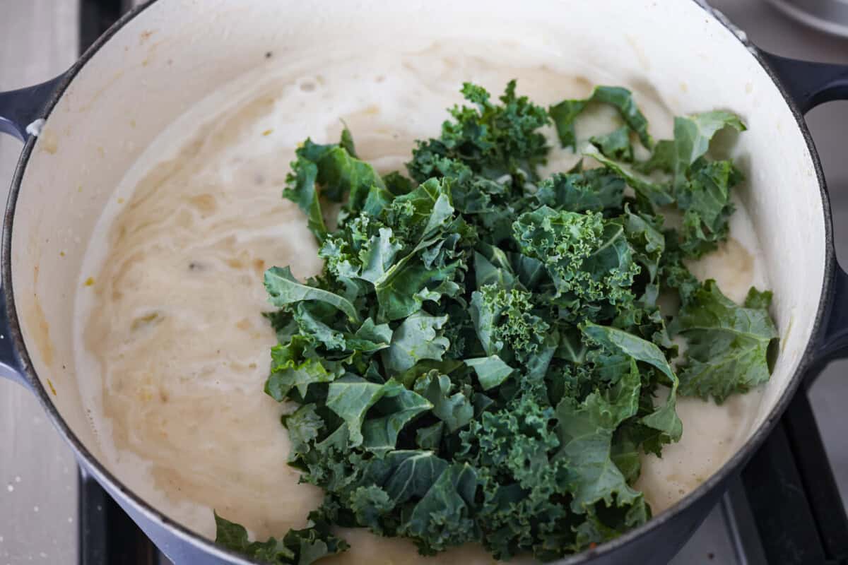 Close up shot of the kale and half and half being added to the colcannon soup. 