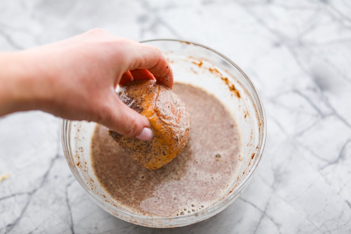 Angle shot of someone dipping a roll into the custard mixture. 