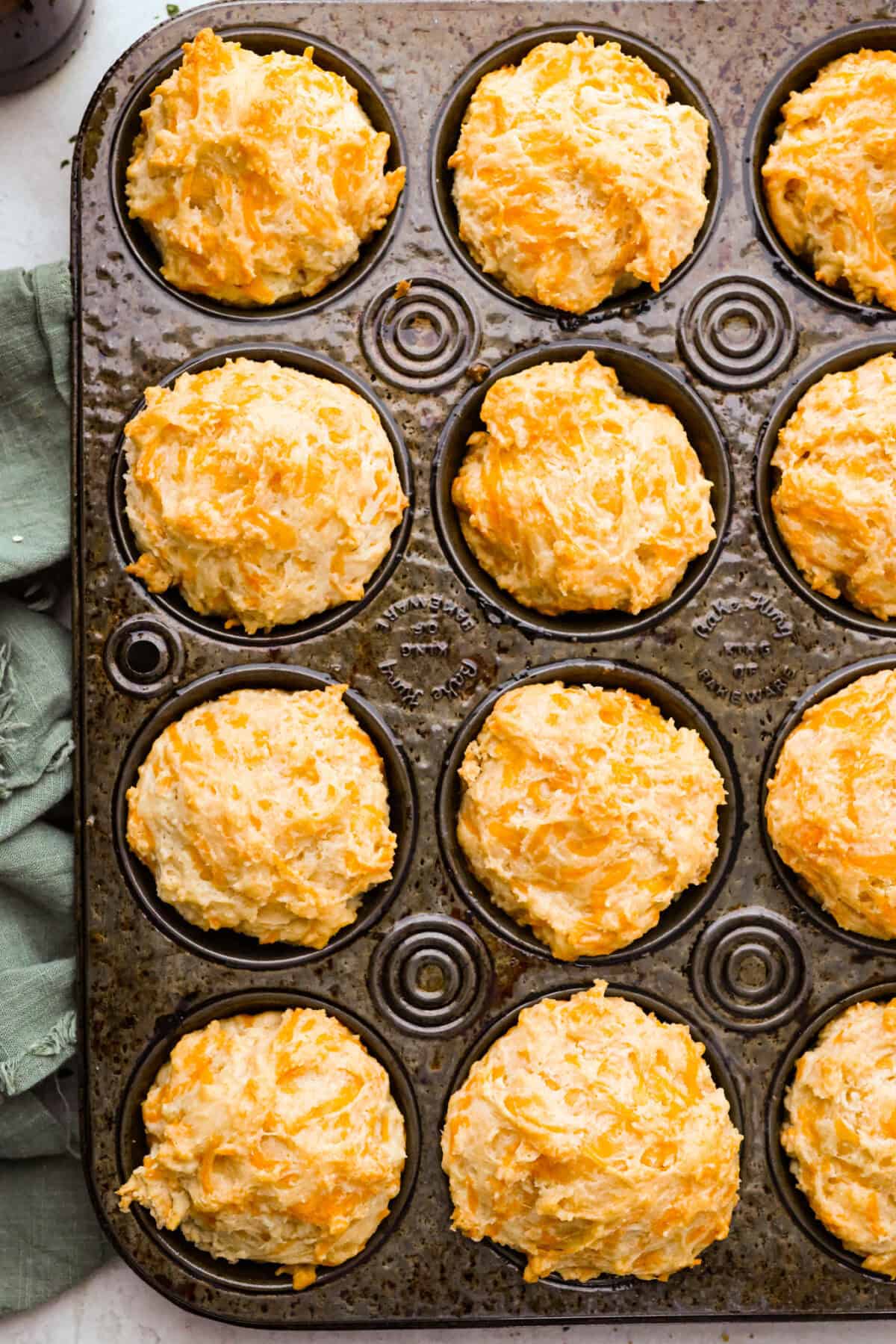 Overhead shot of the baked cheesy beer bread muffins still in the baking tin. 