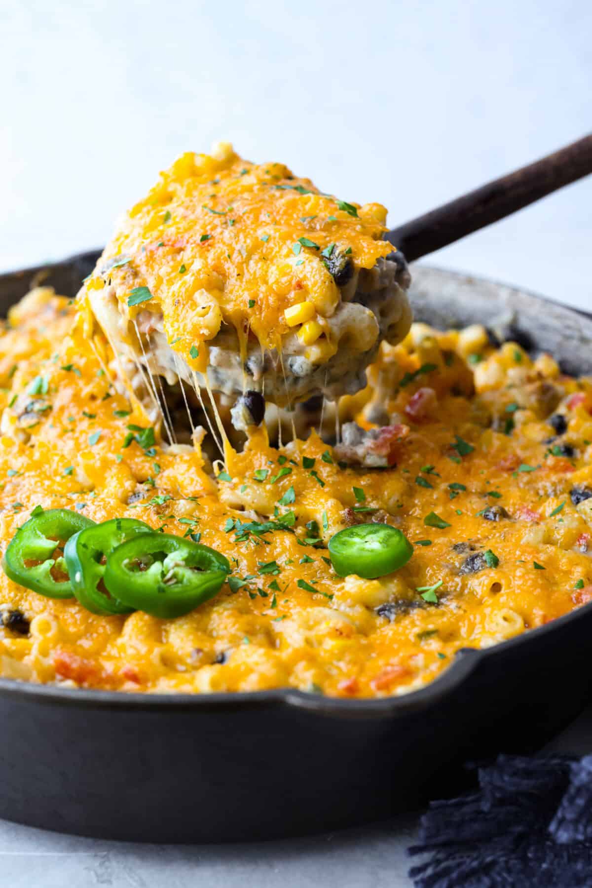 Close up shot of someone pulling a scoop of cowboy mac and cheese out of the skillet. 