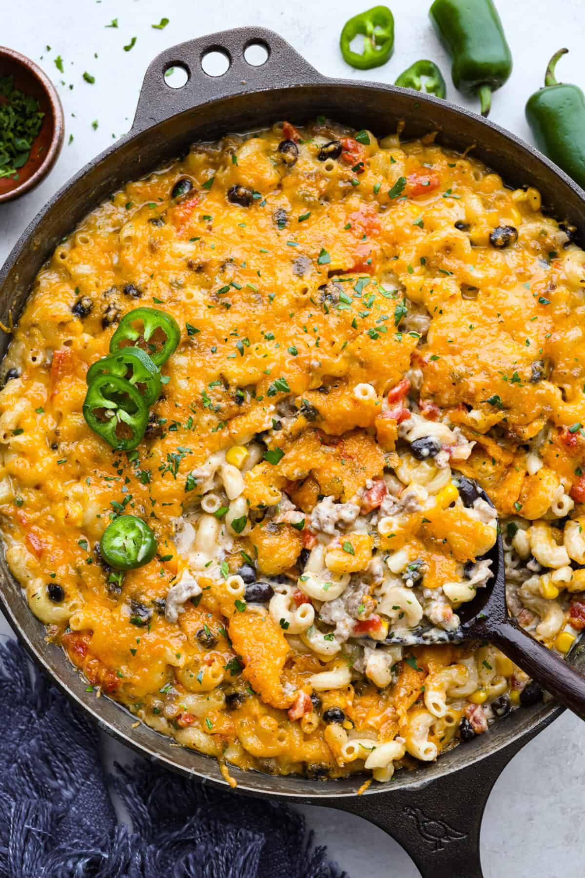 Tops down shot of cowboy mac and cheese in a skillet, garnished with sliced jalapeño. 