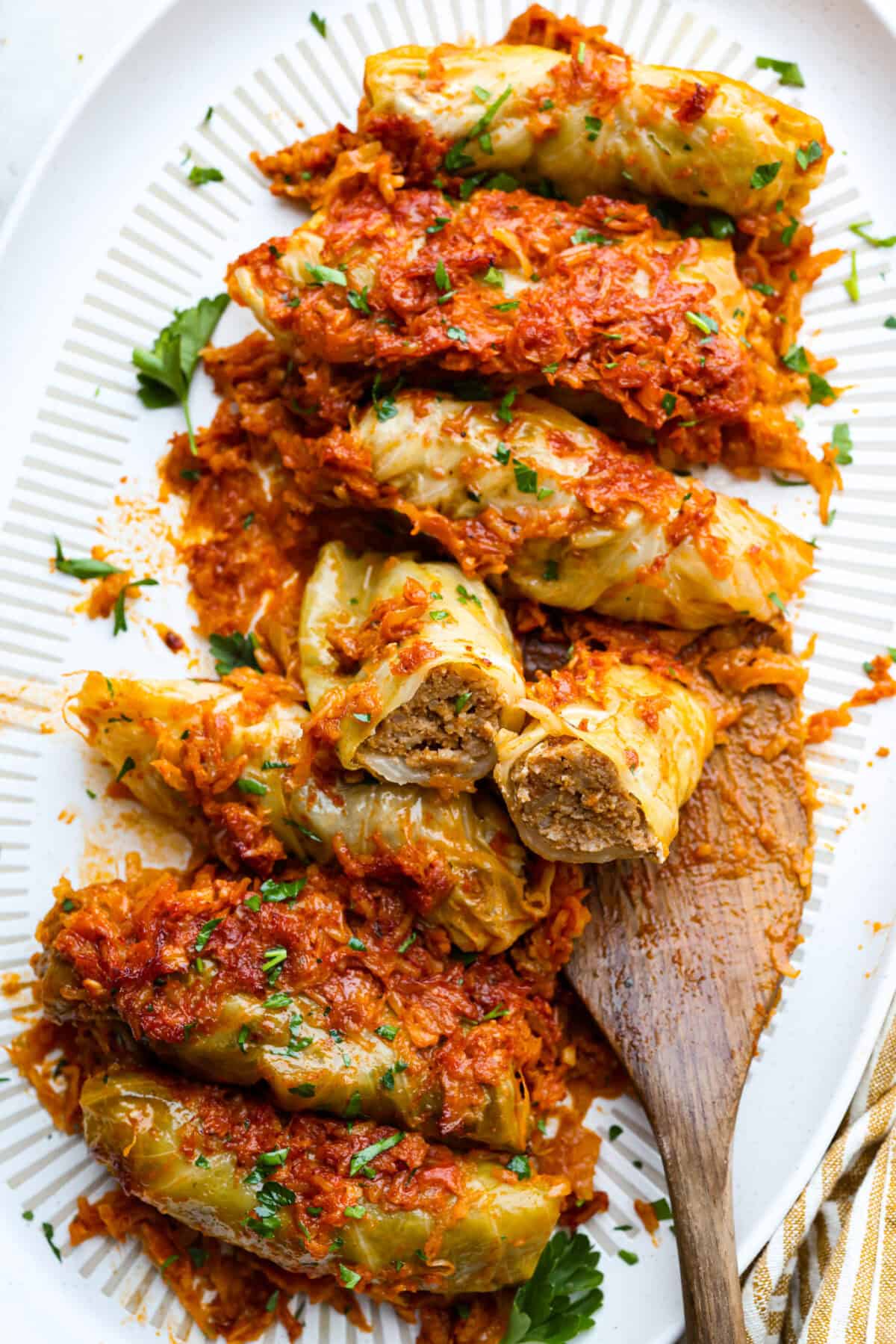 Overhead shot of Hungarian cabbage rolls on a platter with a wooden serving spoon. 