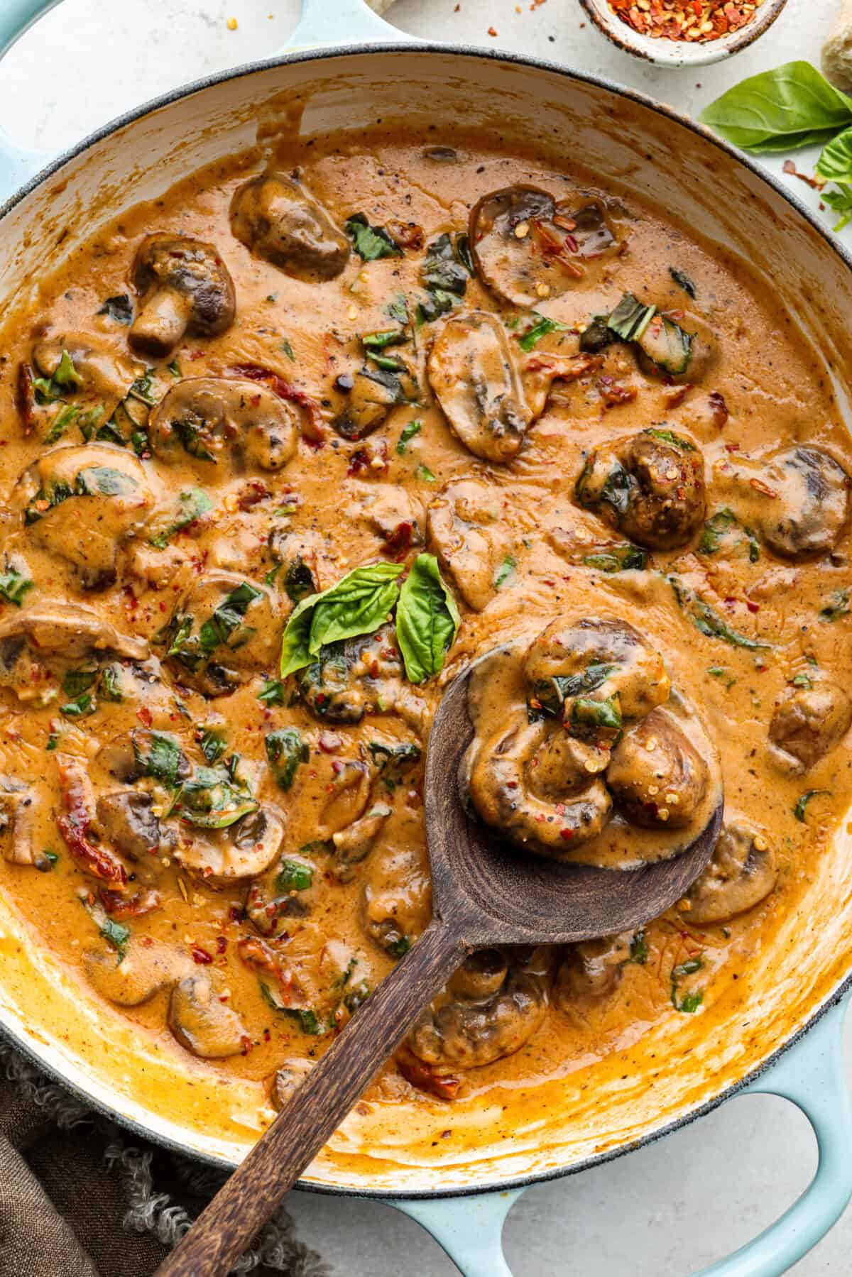 Marry Me mushroom sauce in a skillet with wooden serving spoon scooping out a spoonful. 