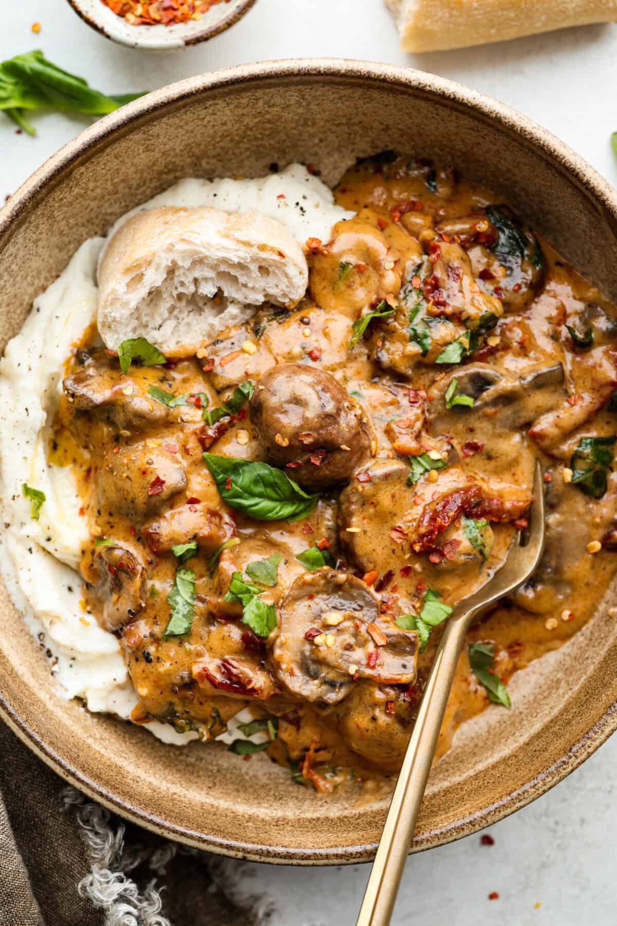 Overhead shot of plated marry me mushrooms over mashed potatoes and a crust of bread. 