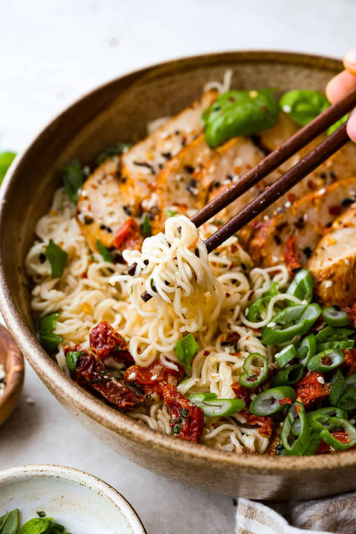 Marry Me Chicken Ramen is the ultimate comfort food mashup you didn’t know you needed! Searing the chicken first locks in moisture and flavor, then it simmers with fresh basil and tangy sun-dried tomatoes in a rich, velvety broth. A bowl of creamy Marry Me Ramen with tender noodles, grilled chicken, sun-dried tomatoes, and fresh green onions. Chopsticks lifting noodles from the rich, flavorful broth.