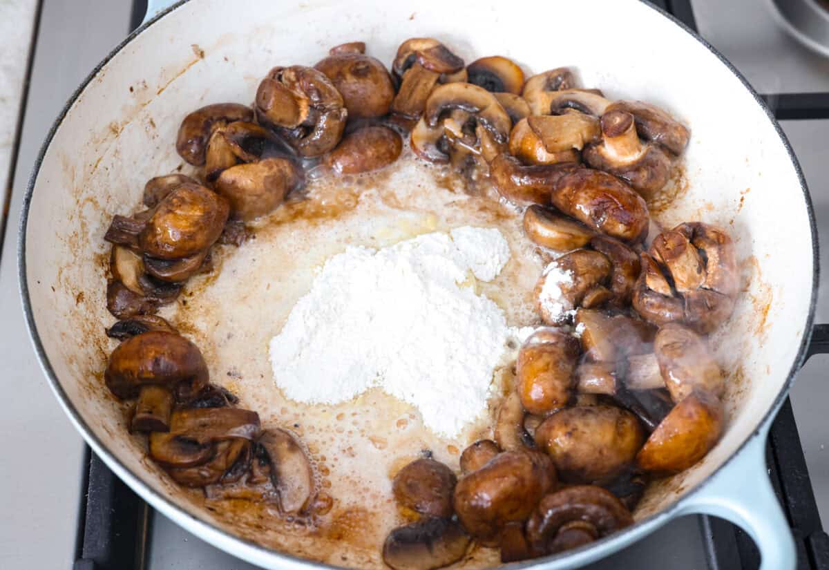 Overhead shot of cooked mushrooms, butter and flour in a skillet. 