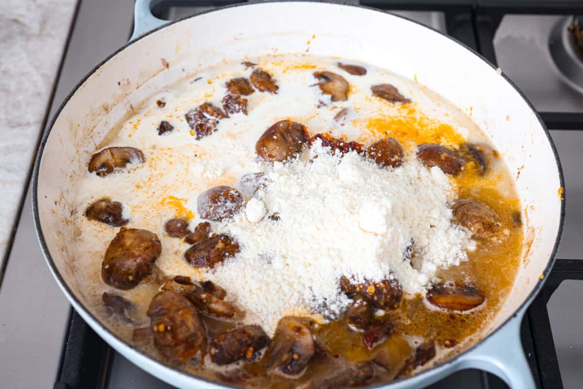 Overhead shot of the cream and parmesan cheese added to the skillet. 