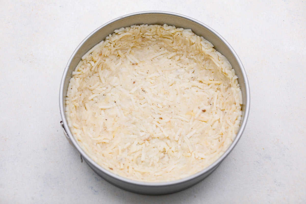 My Hash Brown Crust Quiche is a gluten-free twist on a classic! Crispy, golden potatoes wrap around a rich, savory, custardy filling. Brunch just got an upgrade! Hash brown mixture pressed firmly into the spring form pan.