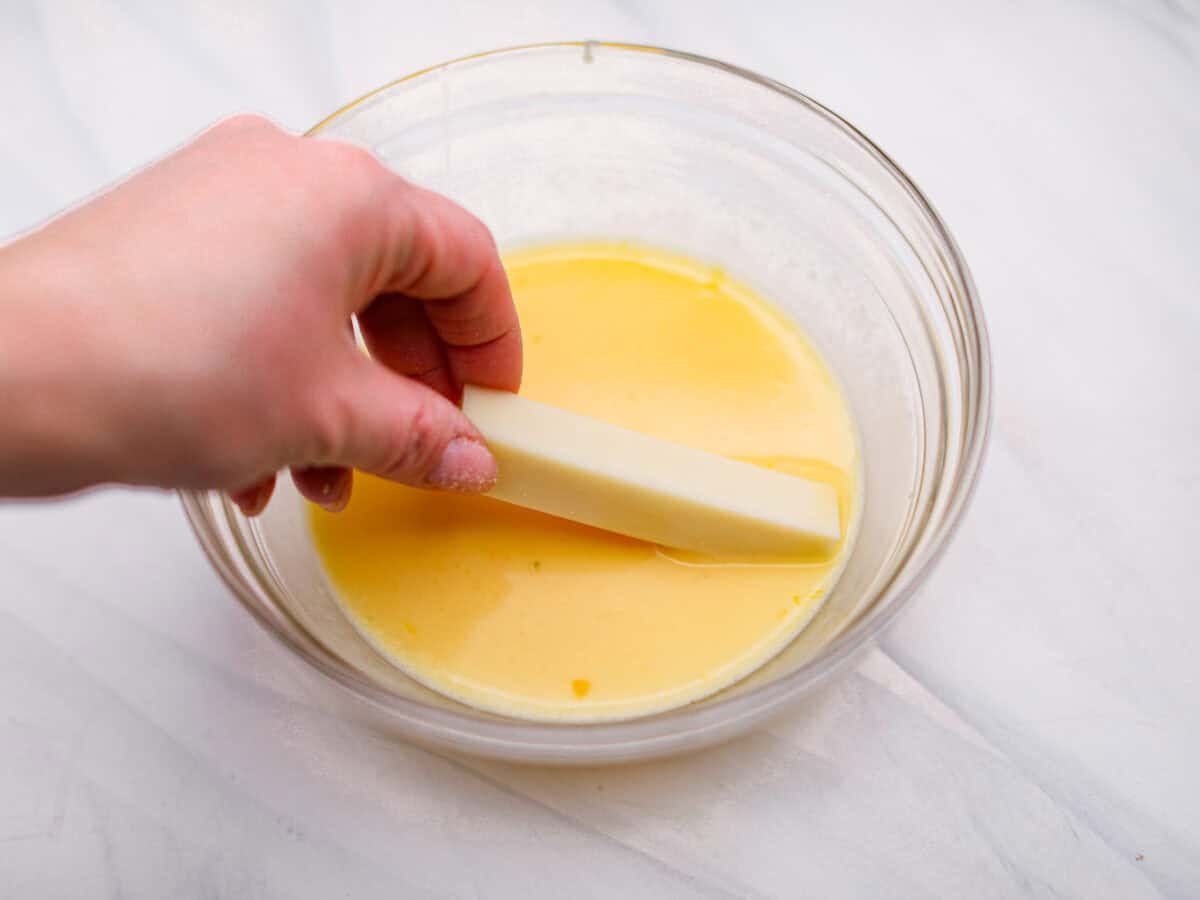 Someone dipping a cheese stick into the egg mixture. 