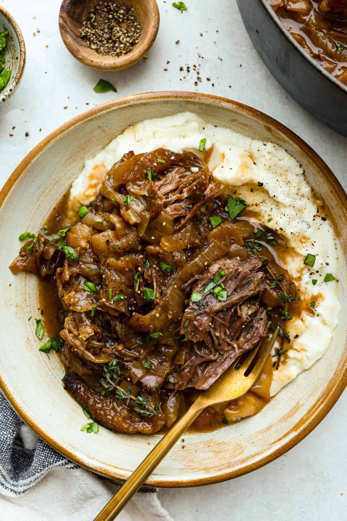 Plate of mashed potatoes and french onion pot roast with a golden spoon. 