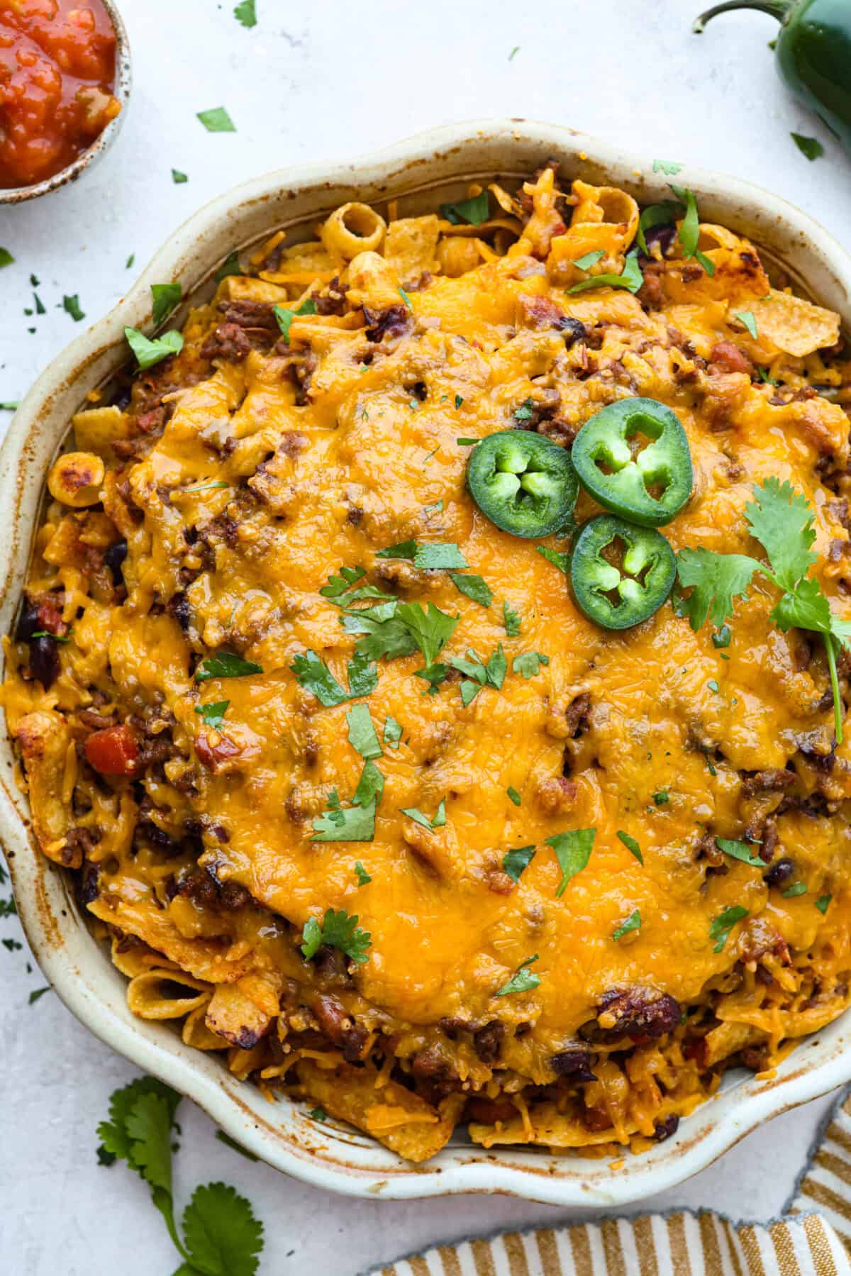 Not to be dramatic, but Frito Chili Pie might have saved my sanity. Zero whining, zero leftovers, it was a total dinner miracle. Crunchy, flavorful and ridiculously easy... you need this in your life ASAP. Overhead shot of Frito chili pie garnished with cilantro and jalapeños.