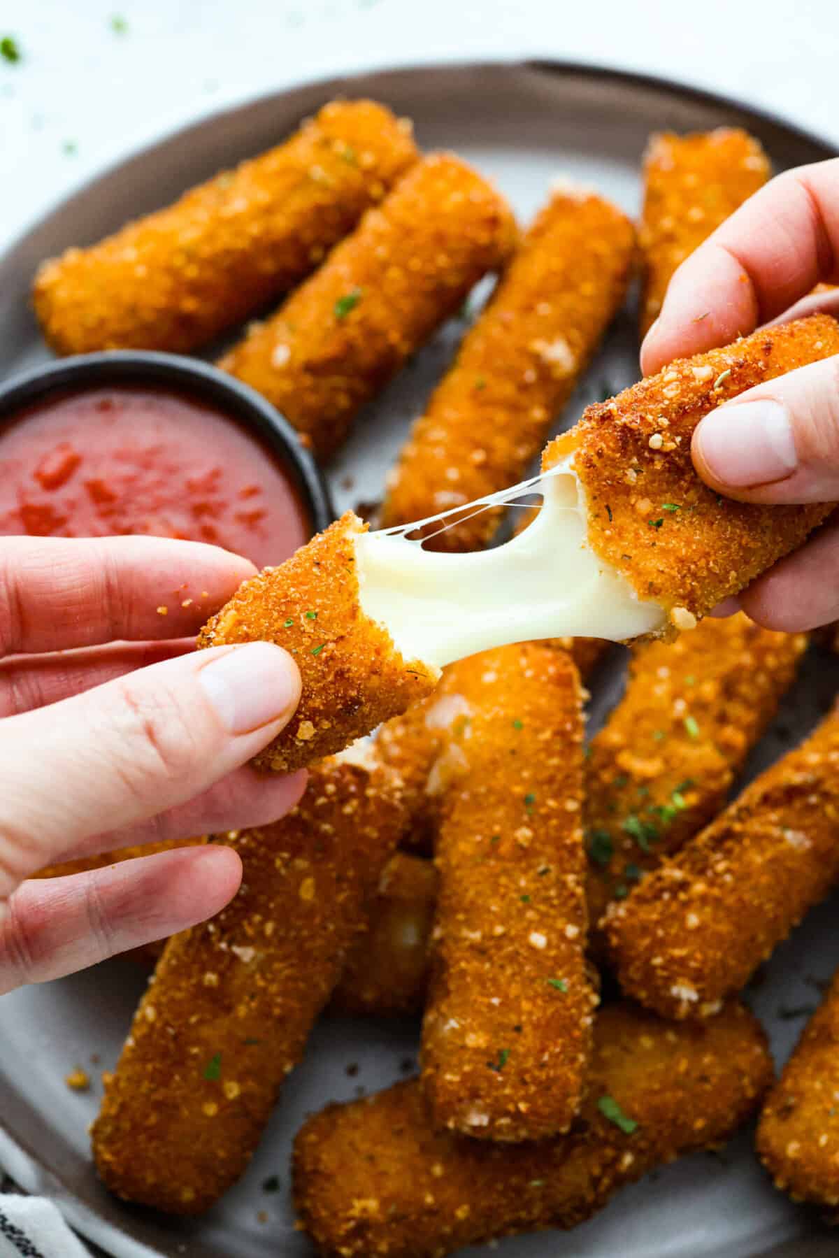 Close up shot of someone pulling and stretching a mozzarella stick apart.