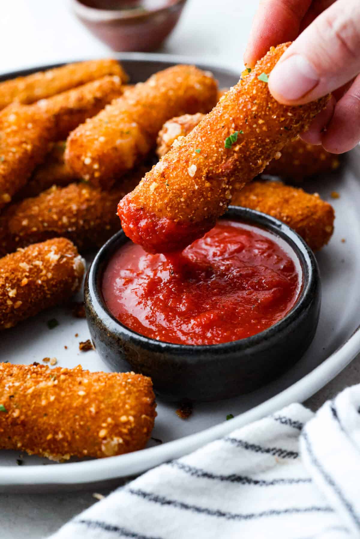 Someone dipping a mozzarella stick into marinara sauce. 