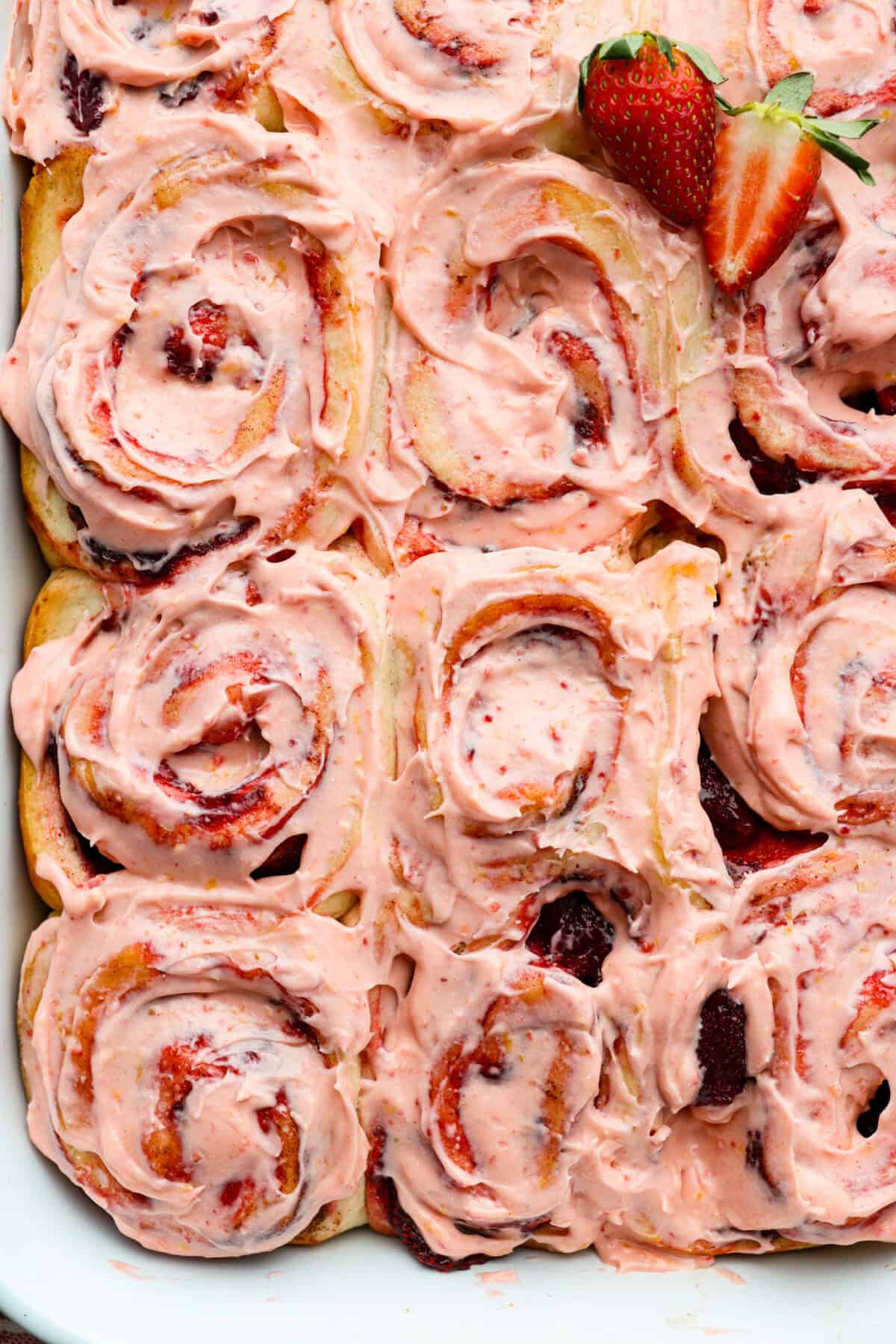 Overhead shot of strawberry cinnamon rolls frosted with lemon cream cheese glaze. 