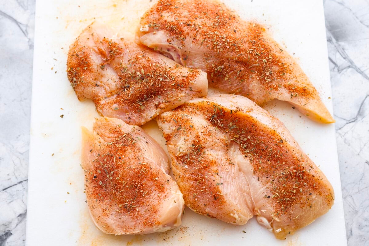 Seasoned chicken on a cutting board. 