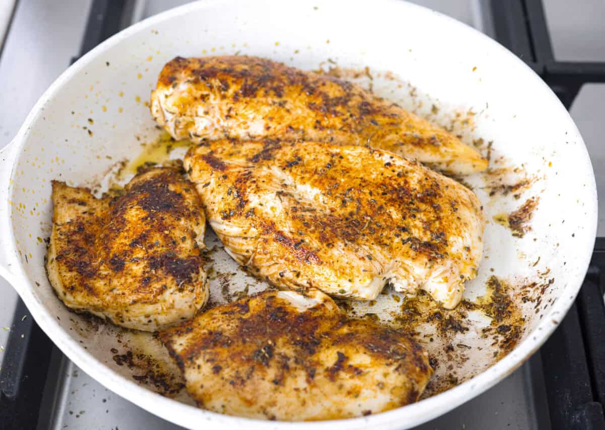 Seasoned chicken cooking in a skillet. 