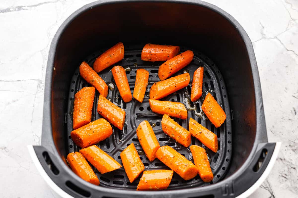 Seasoned carrots in an air fryer basket. 