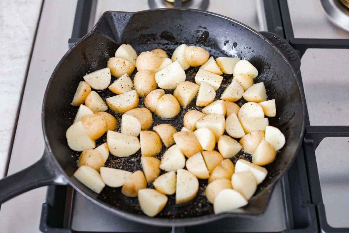 Diced potatoes cooking in a skillet. 