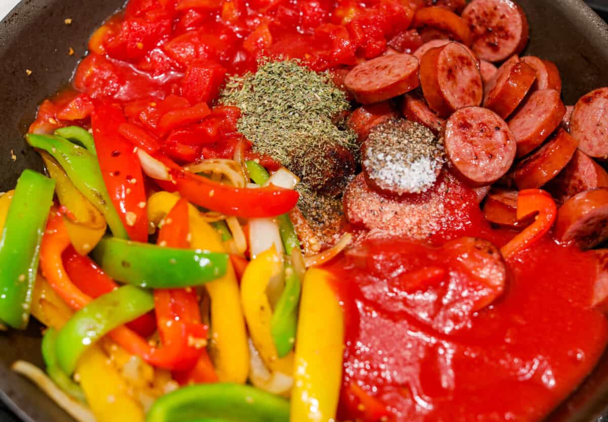 Seasonings, diced tomatoes and tomato sauce added to the vegetables in the skillet along with the sausage. 