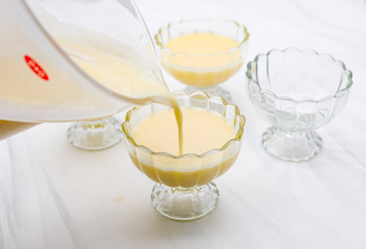 Someone pouring the lemon cream into a glass serving dish. 