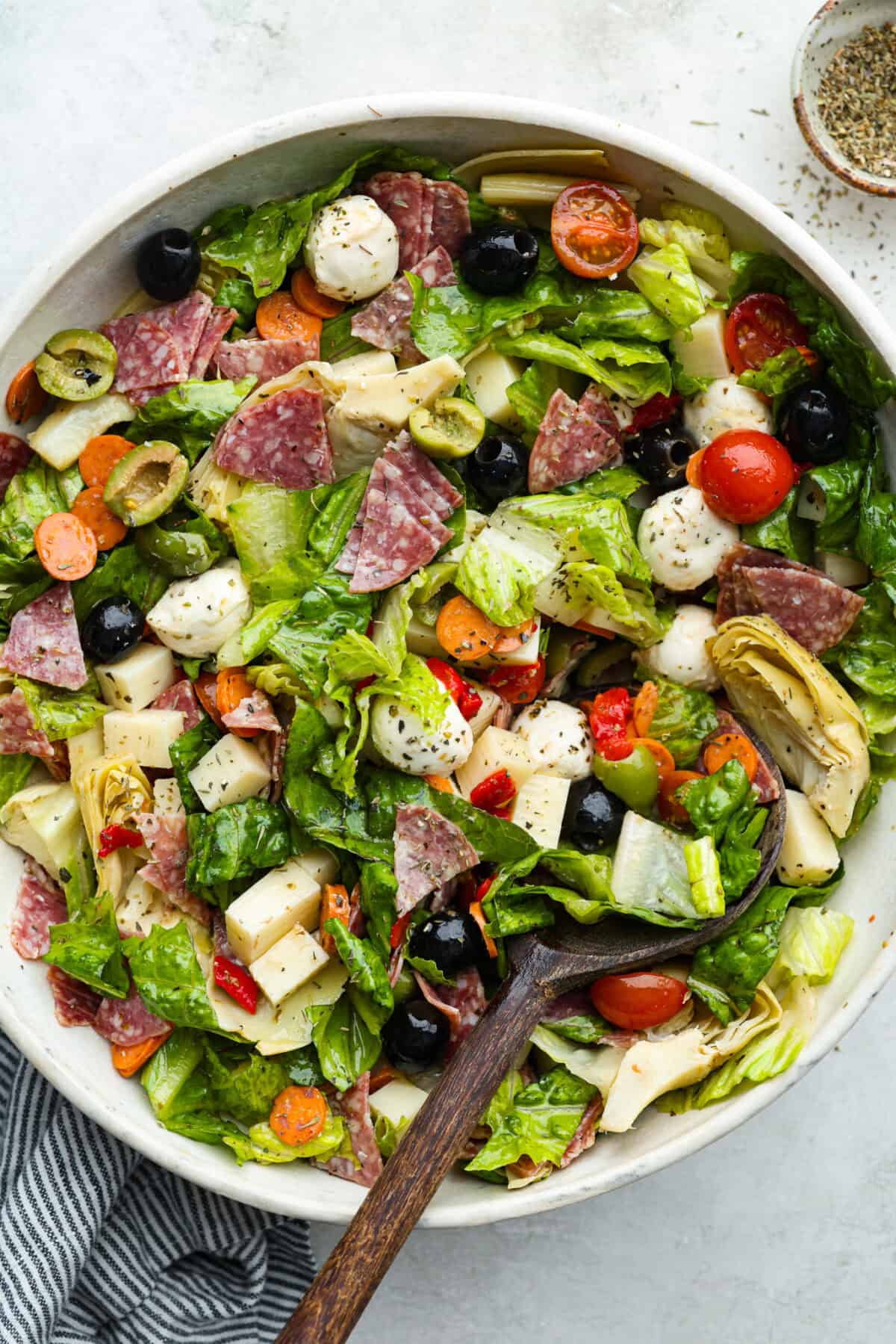 Okay, this antipasto salad? Itโs basically an Italian snack board in a bowl, and Iโmย obsessed! What makes this one a little different (and so good) is the easy lemony dressing. Large bowl of antipasto salad.