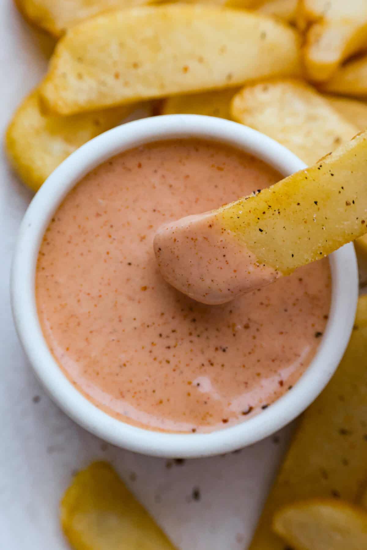 Someone dipping a fry into the fry sauce. 