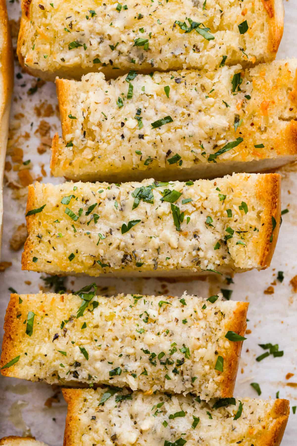 Iโm not saying Iโve eaten half a loaf of this Garlic Bread straight off the baking sheetโฆbut Iโm also not not saying that. Itโs golden, cheesy, dripping with garlicky butter, and so good! Close up shot of garlic bread straight from the oven.