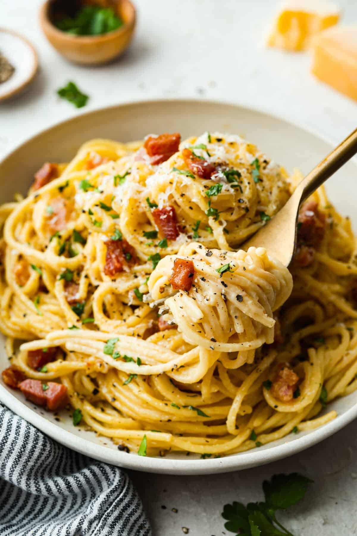 A forkful of pasta carbonara over the plated dish. 