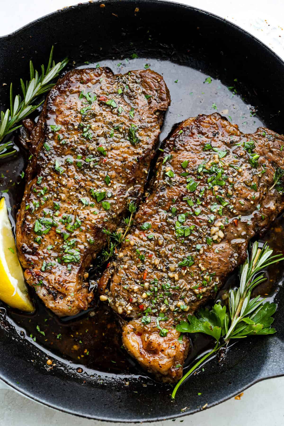 Two Steaks in a skillet with steak marinade. 
