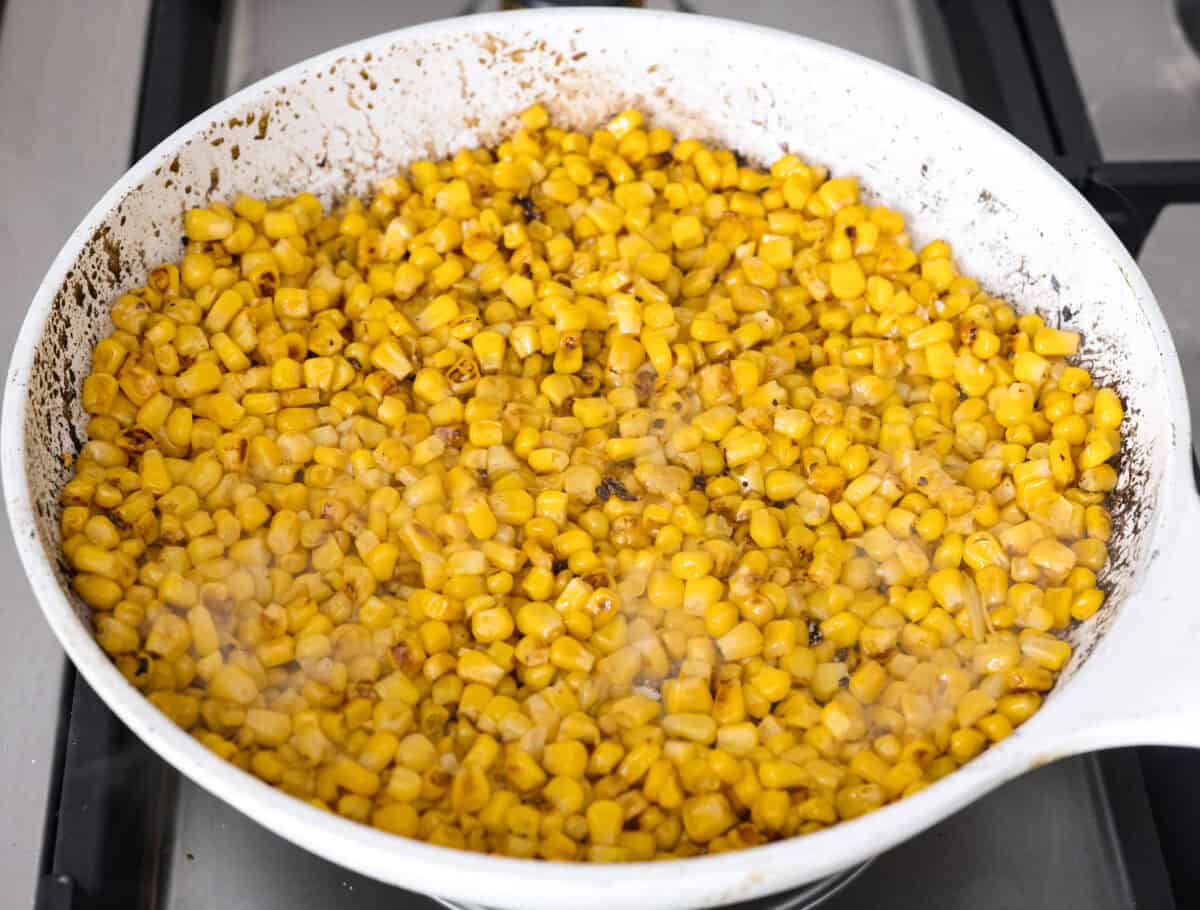 Guys, I’m obsessed with elote, so obviously I had to turn all that smoky, creamy, cheesy, limey magic into a pasta salad big enough to feed a crowd. This one’s guaranteed to disappear fast! Corn sautéing in a skillet.