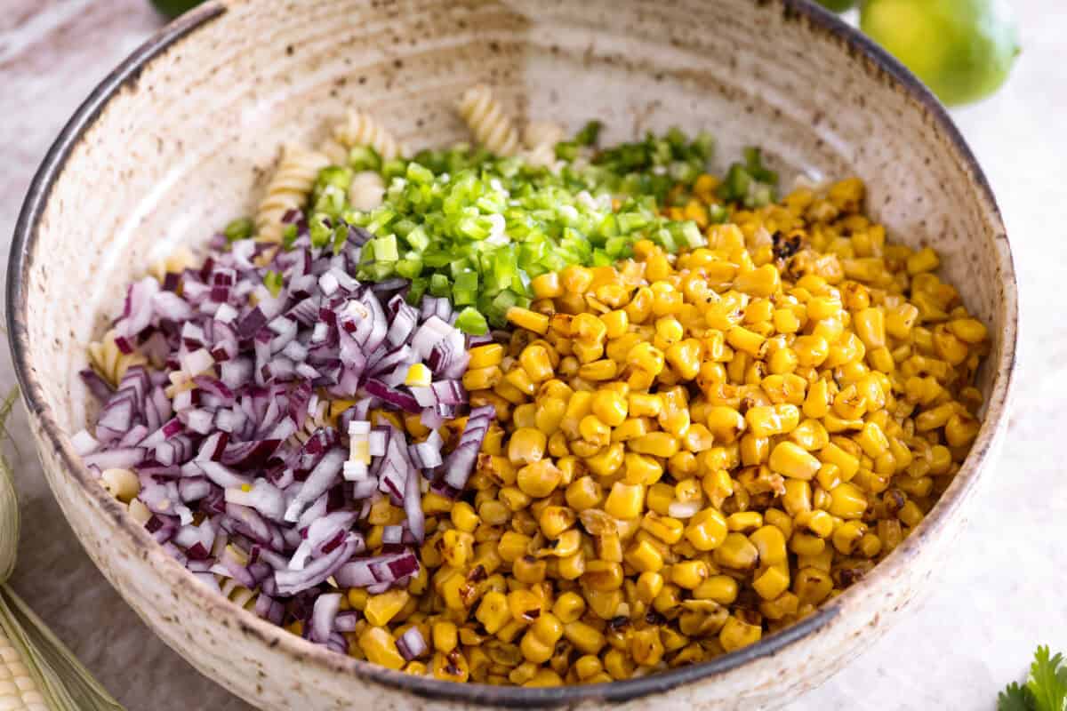 Guys, I’m obsessed with elote, so obviously I had to turn all that smoky, creamy, cheesy, limey magic into a pasta salad big enough to feed a crowd. This one’s guaranteed to disappear fast! Cooked pasta with diced onion, jalapeno, and corn added to it.