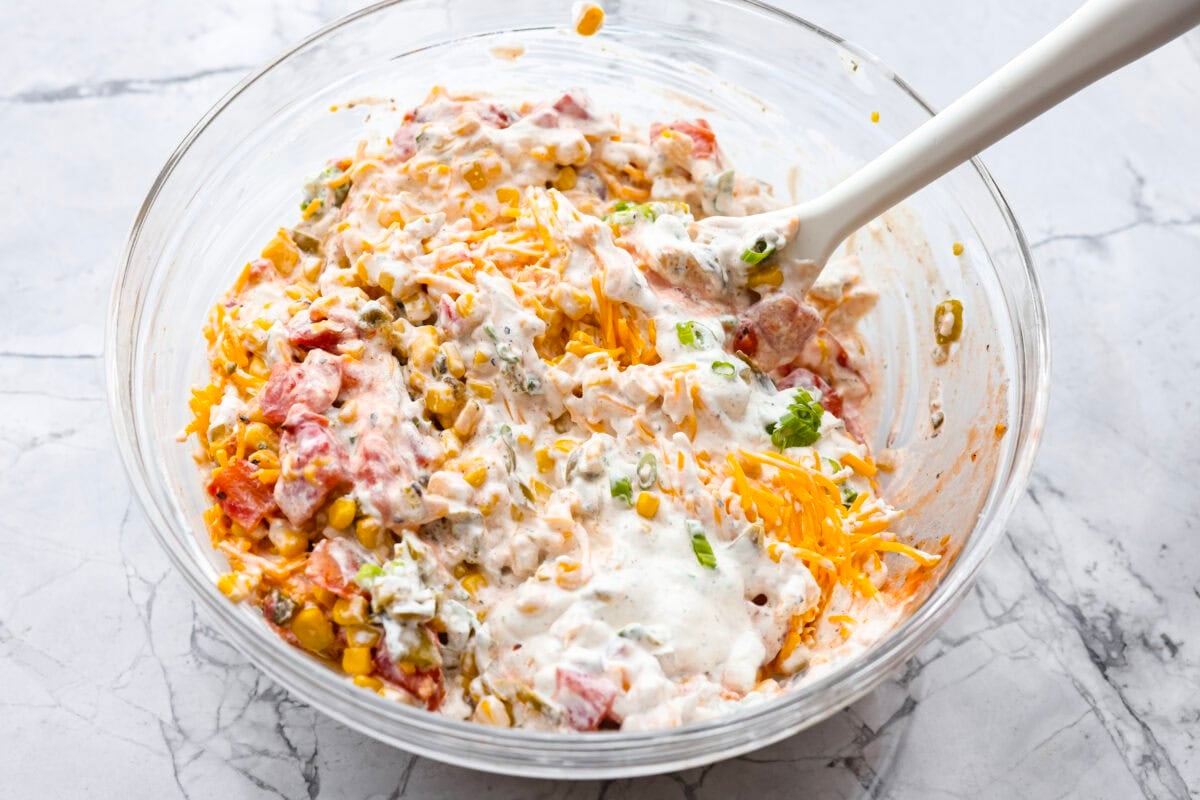 Crack Corn Dip is creamy, cheesy, and loaded with bold flavor! Sweet corn and a custom spice blend give it a fun twist, making it the ultimate scoopable snack for summer hangouts. Veggie and cheese mixture mixed with the sauce.
