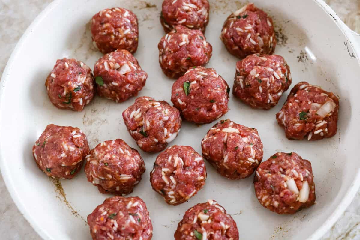 Meatballs shaped in in a skillet. 