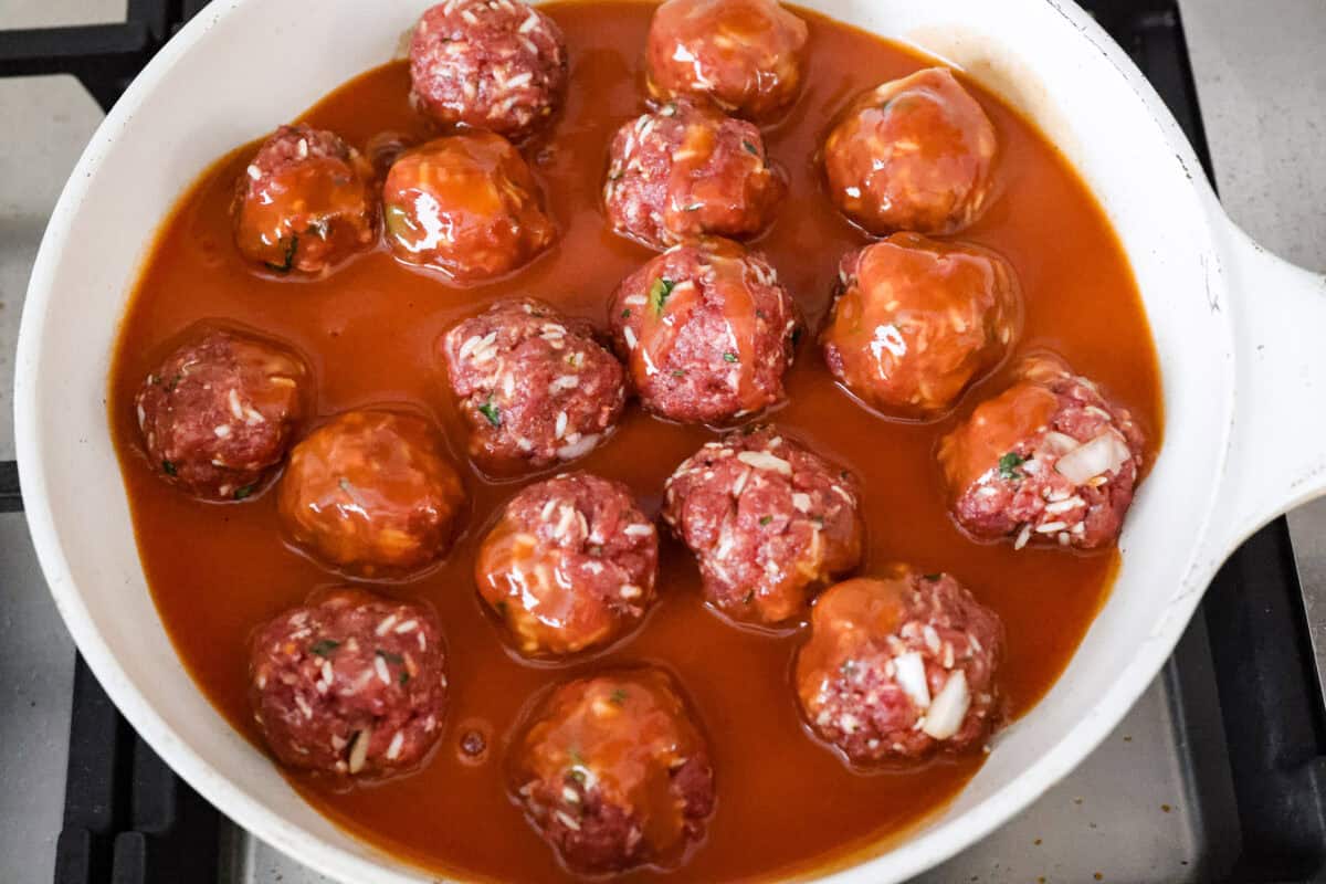 Sauce poured over meatballs in the skillet.