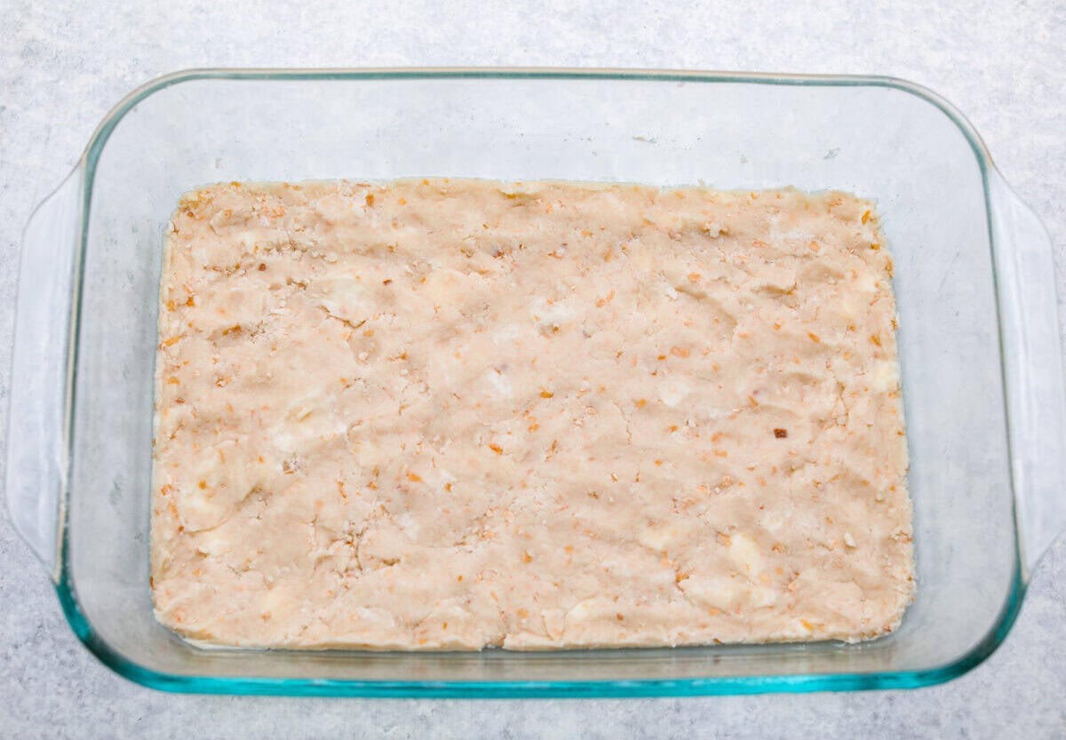 My Dad LOVES coconut cream pie! When I don't have it in me to make a pie, I make this easy Coconut Lush dessert! It’s rich, dreamy, and always the first dessert to disappear at family gatherings. crust ingredients smashed at the bottom of a baking dish.