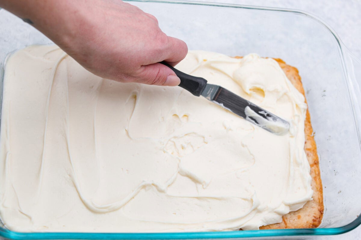 My Dad LOVES coconut cream pie! When I don't have it in me to make a pie, I make this easy Coconut Lush dessert! It’s rich, dreamy, and always the first dessert to disappear at family gatherings. Someone spreading the cream cheese mixture on top of he crust.