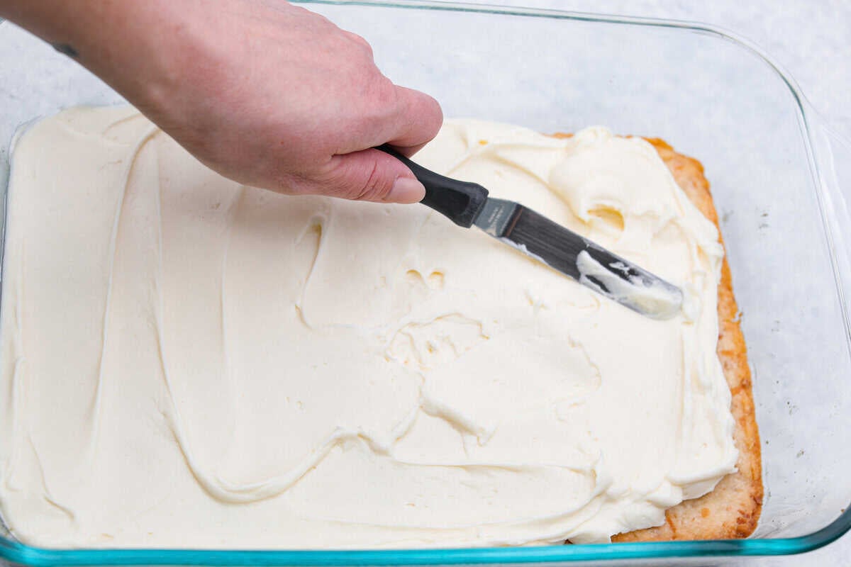 My Dad LOVES coconut cream pie! When I don't have it in me to make a pie, I make this easy Coconut Lush dessert! It’s rich, dreamy, and always the first dessert to disappear at family gatherings. Someone spreading the cream cheese mixture on top of he crust.