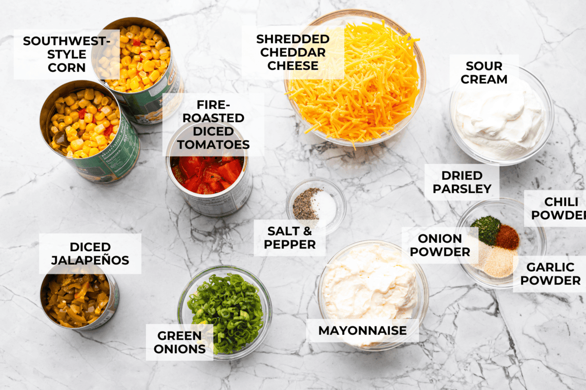 Crack Corn Dip is creamy, cheesy, and loaded with bold flavor! Sweet corn and a custom spice blend give it a fun twist, making it the ultimate scoopable snack for summer hangouts. Overhead shot of labeled ingredients.
