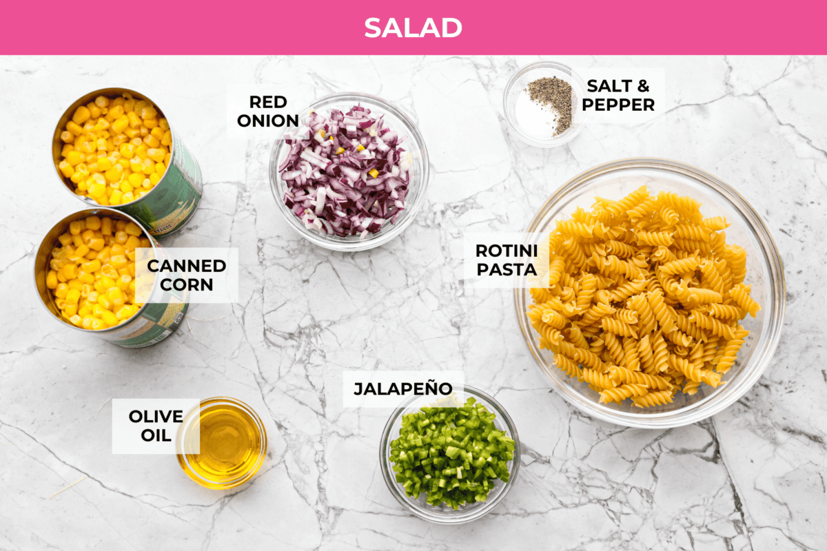 Guys, I’m obsessed with elote, so obviously I had to turn all that smoky, creamy, cheesy, limey magic into a pasta salad big enough to feed a crowd. This one’s guaranteed to disappear fast! Overhead shot of labeled salad ingredients.