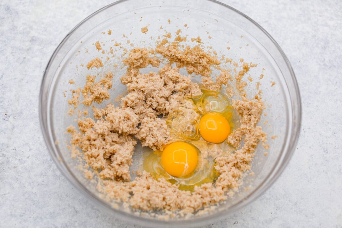 Butter, sugar and brown sugar mixed together in a bowl with tow cracked eggs. 