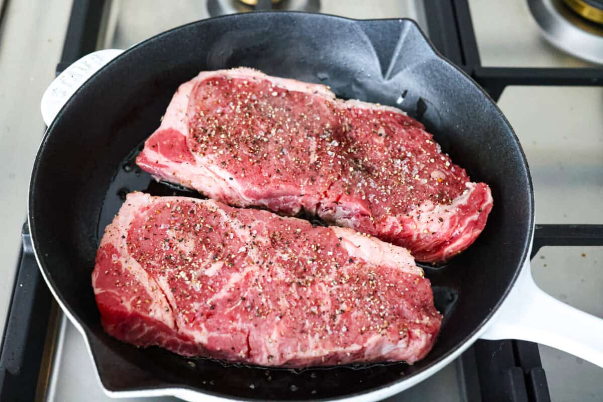 Seasoned steak searing in a skillet. 