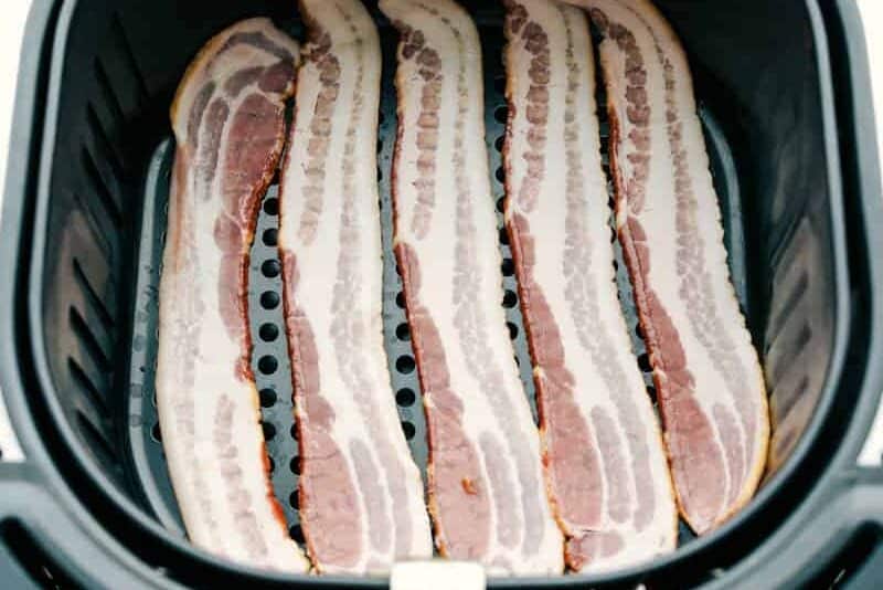 Overhead shot of raw bacon in the air fryer basket.