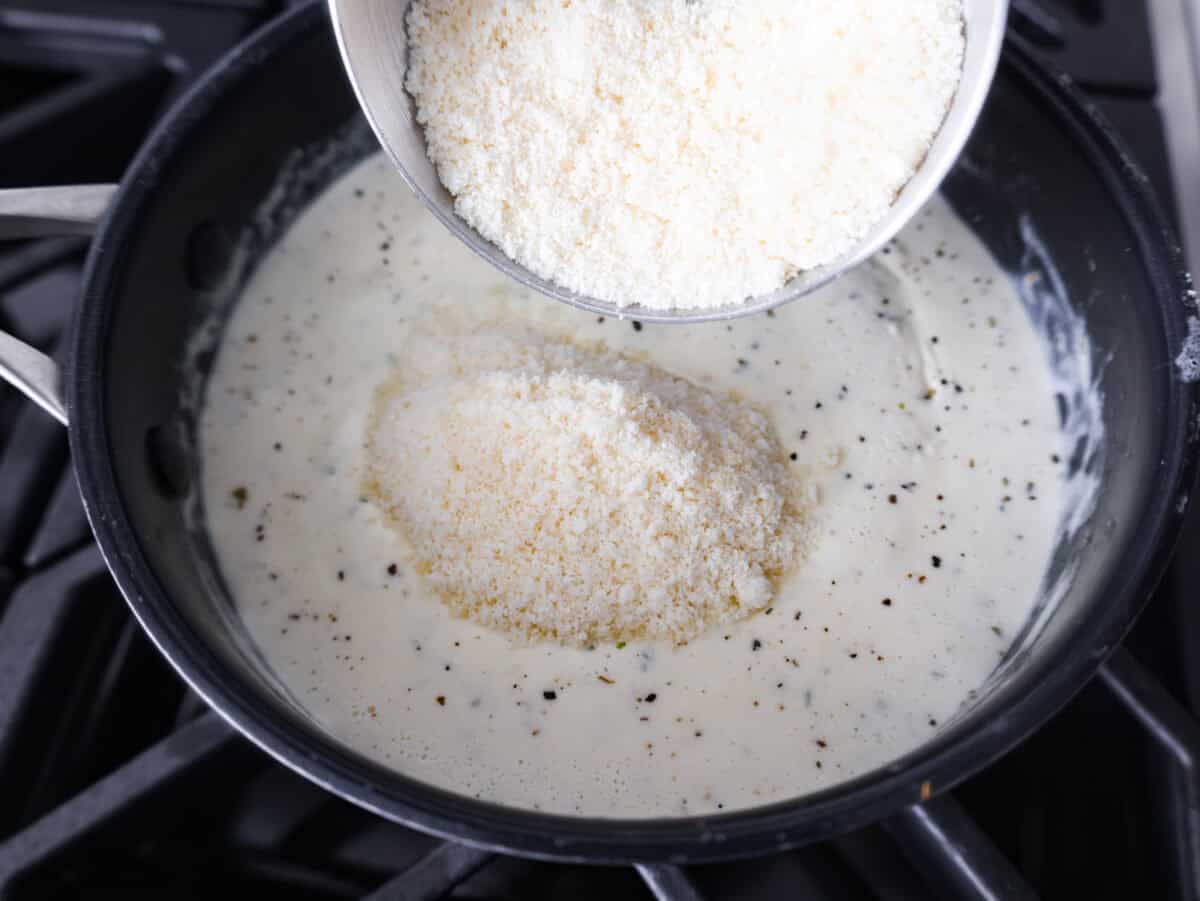 Alfredo sauce is one of my most popular recipes EVER! The secret is a little cream cheese, and ohhh my gosh, the tangy creaminess takes it to the next level. You and your kids will inhale it, I promise! Parmesan cheese being added to the cream and seasoning mixture.