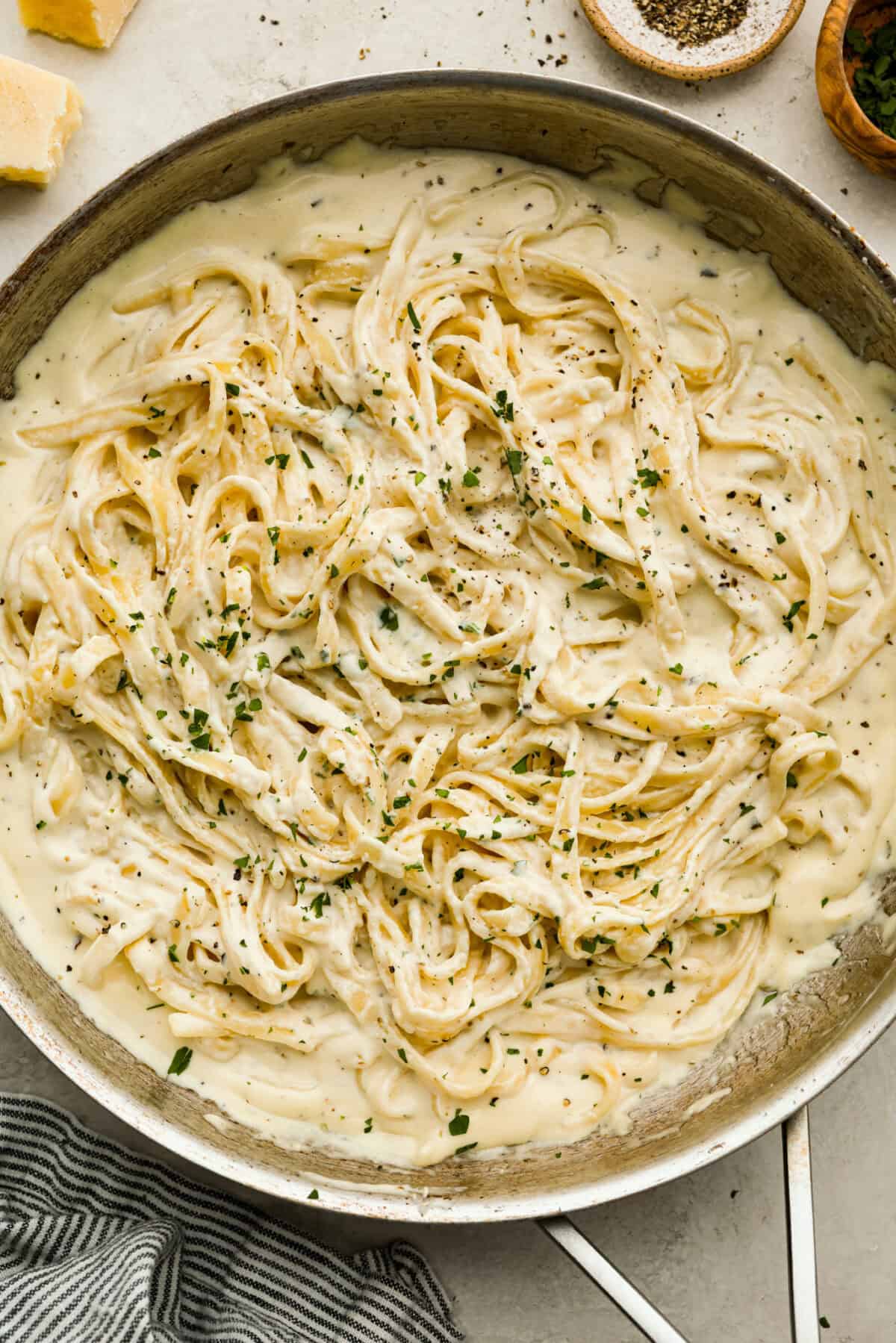 Alfredo sauce is one of my most popular recipes EVER! The secret is a little cream cheese, and ohhh my gosh, the tangy creaminess takes it to the next level. You and your kids will inhale it, I promise! Overhead shot of creamy dreamy homemade Alfredo sauce mixed with pasta in a pan.