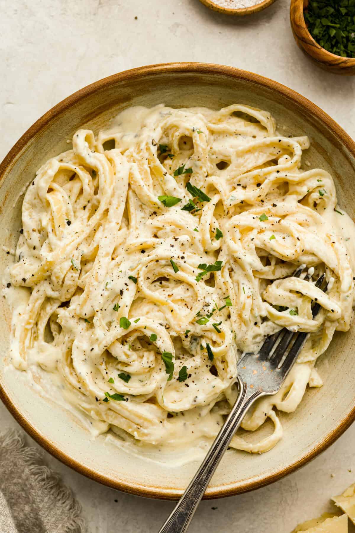 Alfredo sauce is one of my most popular recipes EVER! The secret is a little cream cheese, and ohhh my gosh, the tangy creaminess takes it to the next level. You and your kids will inhale it, I promise! Bowl of fettuccini Alfredo.