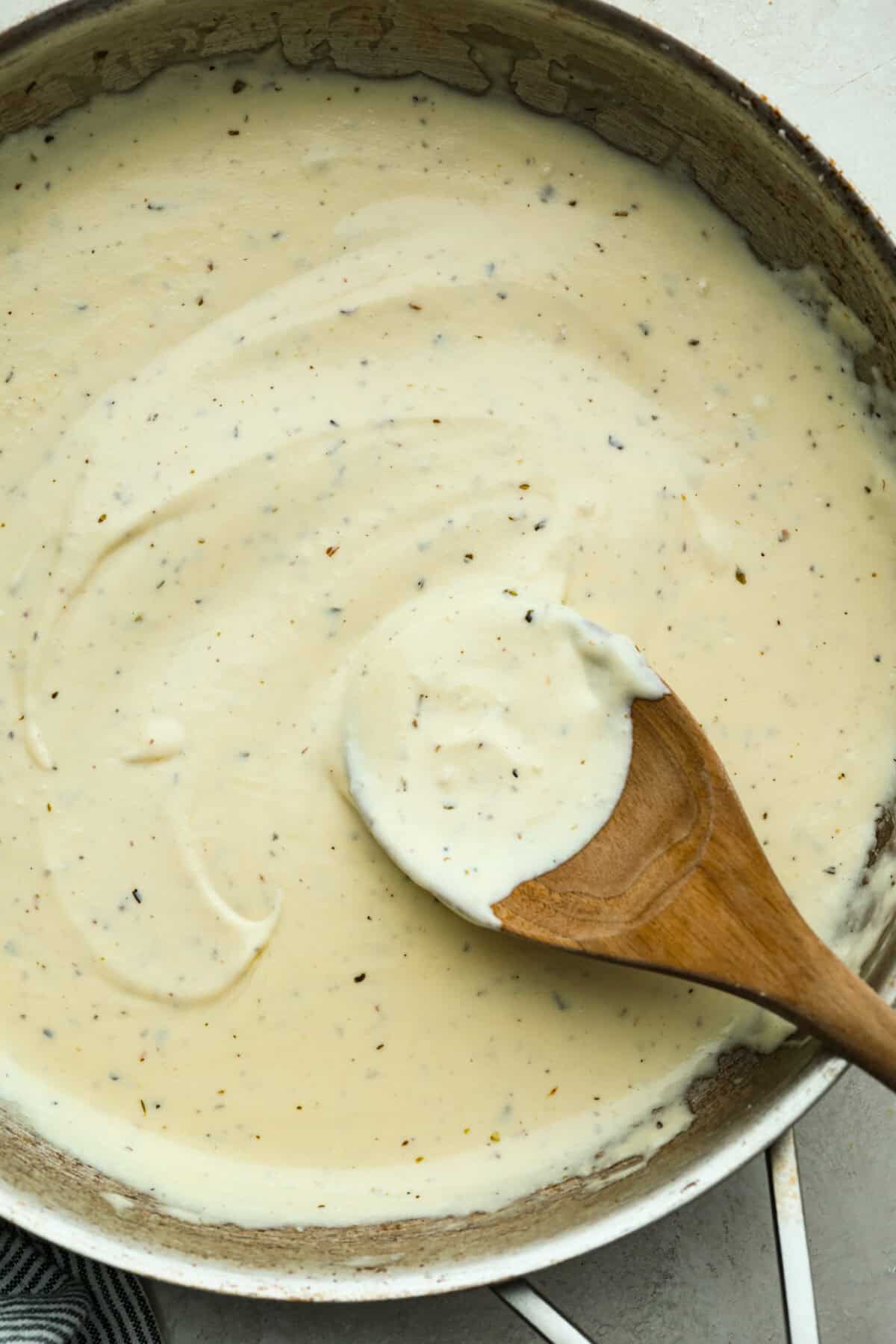 Alfredo sauce is one of my most popular recipes EVER! The secret is a little cream cheese, and ohhh my gosh, the tangy creaminess takes it to the next level. You and your kids will inhale it, I promise! Overhead shot of homemade Alfredo sauce in a pan.