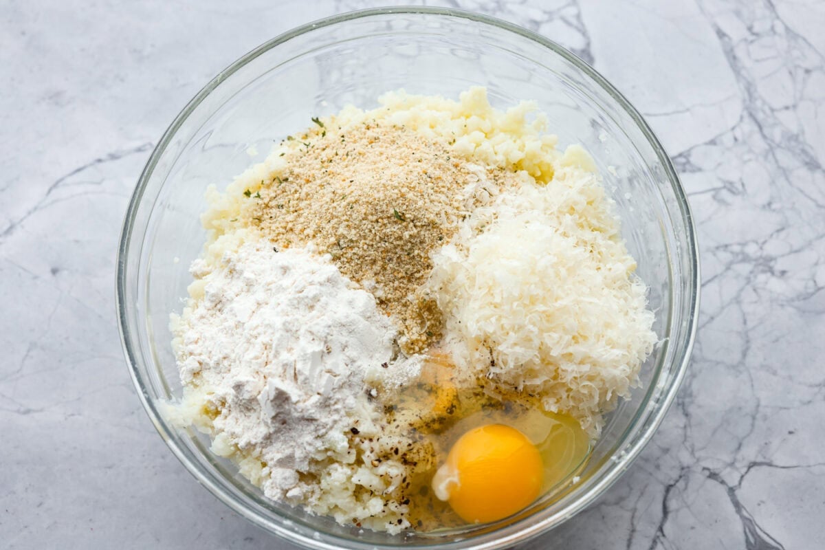 These crispy cauliflower fritters are how I trick my kids into eating veggies. They even ask for seconds. The parmesan and savory seasonings make these golden, cheesy, and packed with flavor! Seasonings, breadcrumbs and egg added to the mashed up cauliflower.