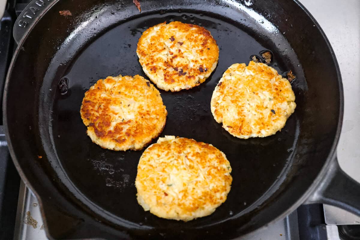 These crispy cauliflower fritters are how I trick my kids into eating veggies. They even ask for seconds. The parmesan and savory seasonings make these golden, cheesy, and packed with flavor! Patties frying in a skillet.